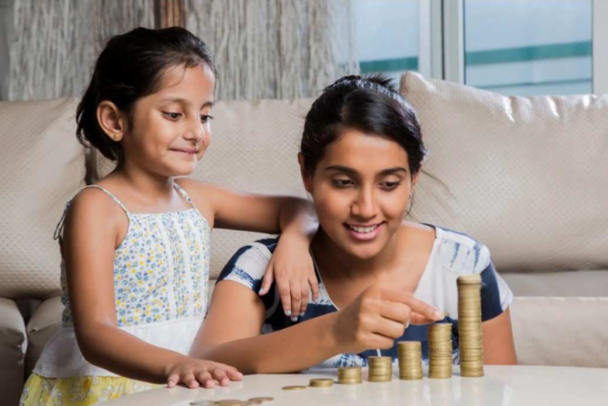 Mother teaching her daughter about saving money by stacking coins